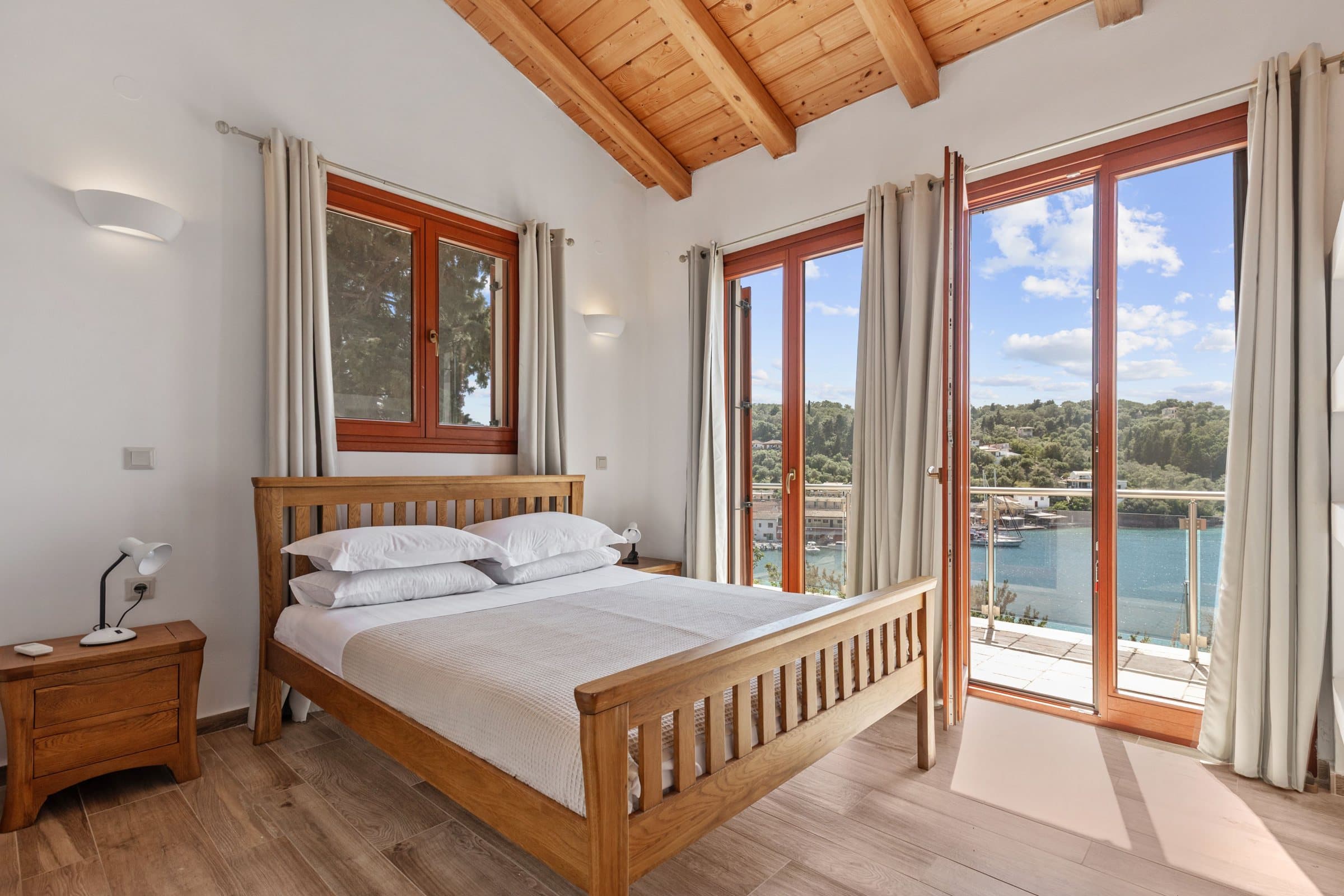 The Sea Room: king bed under timber beams with French windows onto a balcony over the bay